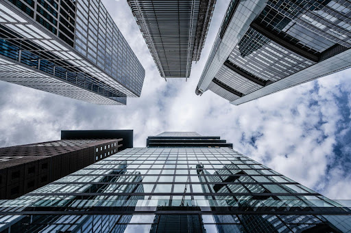 Modern Commercial High-Rise Buildings In Bel Air With Reflective Glass Facades And Iconic Architecture Framing A Cloud-Filled Sky For Premium Real Estate Opportunities.
