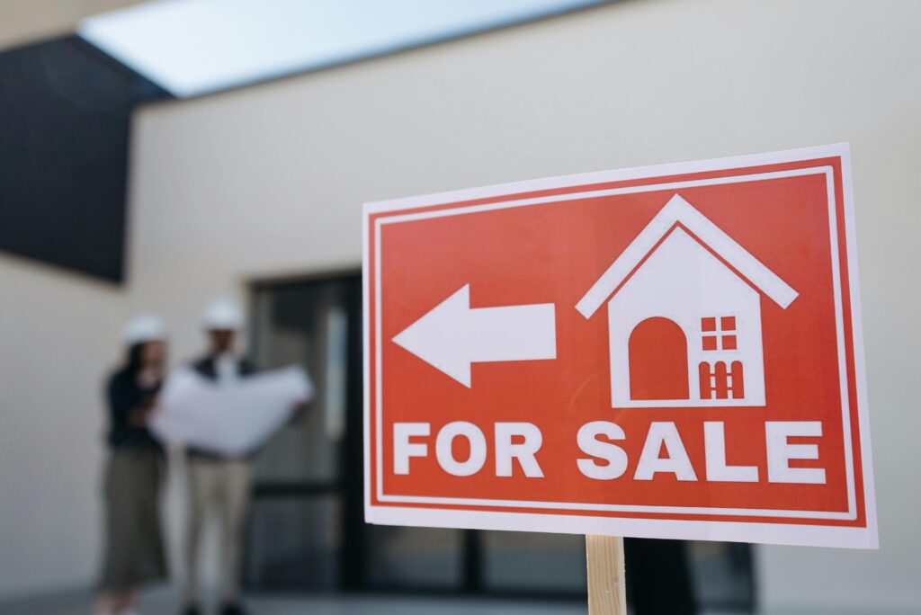 Orange Real Estate For Sale Sign With White House Symbol And Directional Arrow Outside Residential Property.