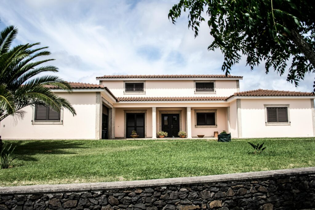 Luxury Mediterranean Style Home For Sale With Manicured Lawn And Stone Wall In Exclusive Los Angeles Neighborhood.