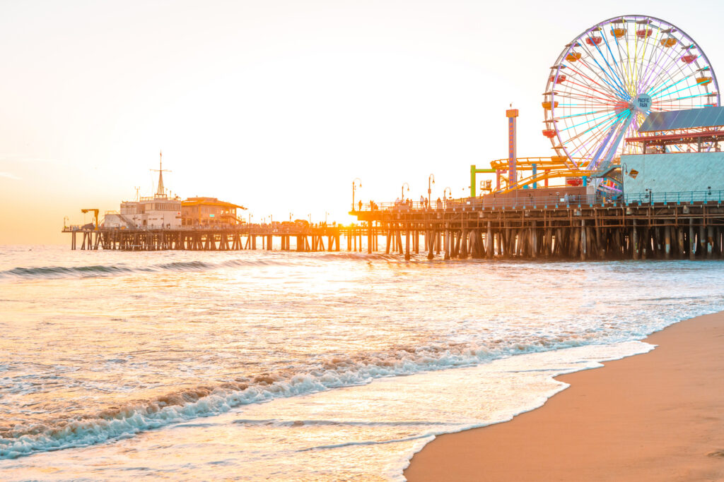 Santa Monica Pier At Sunset With Iconic Ferris Wheel And Amusement Park Over Pacific Ocean Beach Showcasing Premium Coastal Living Location.